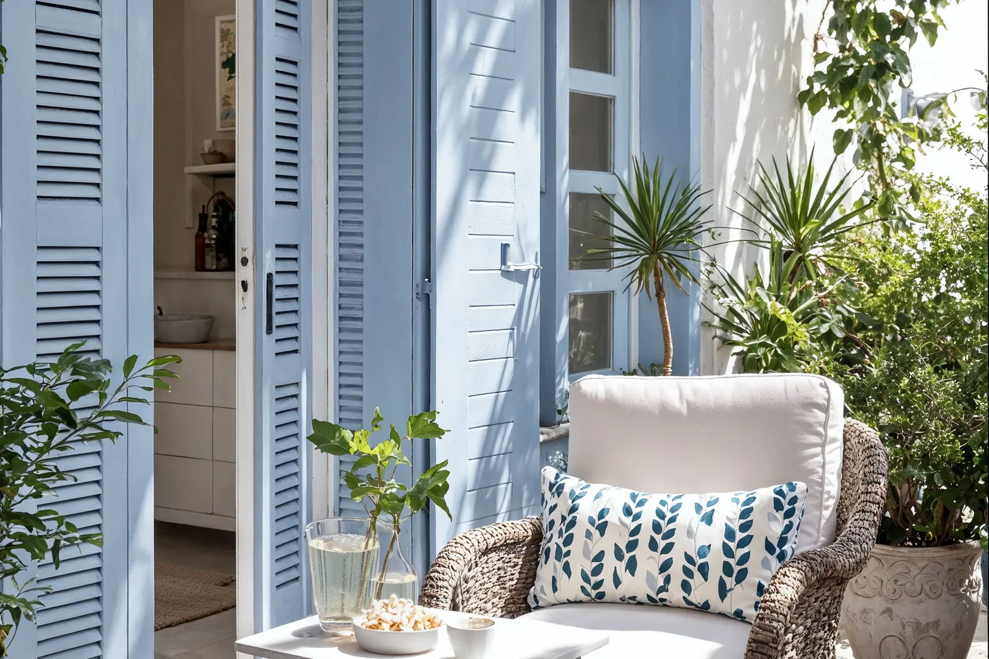 Terraza con contraventanas azules y mobiliario de mimbre, estilo mediterráneo