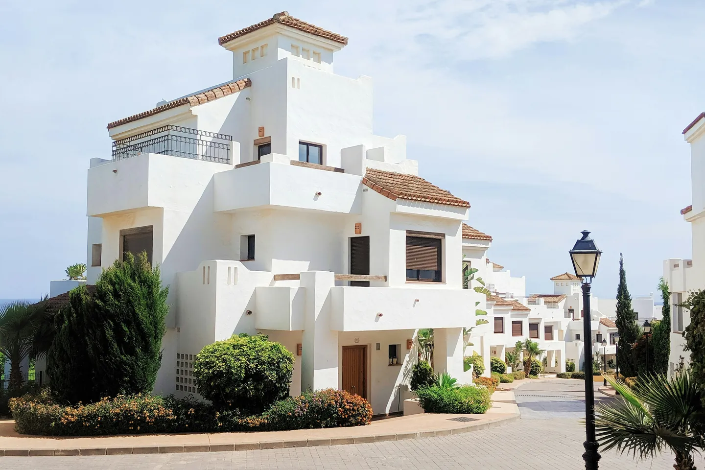 Calle de urbanización mediterránea con viviendas blancas y cielo despejado